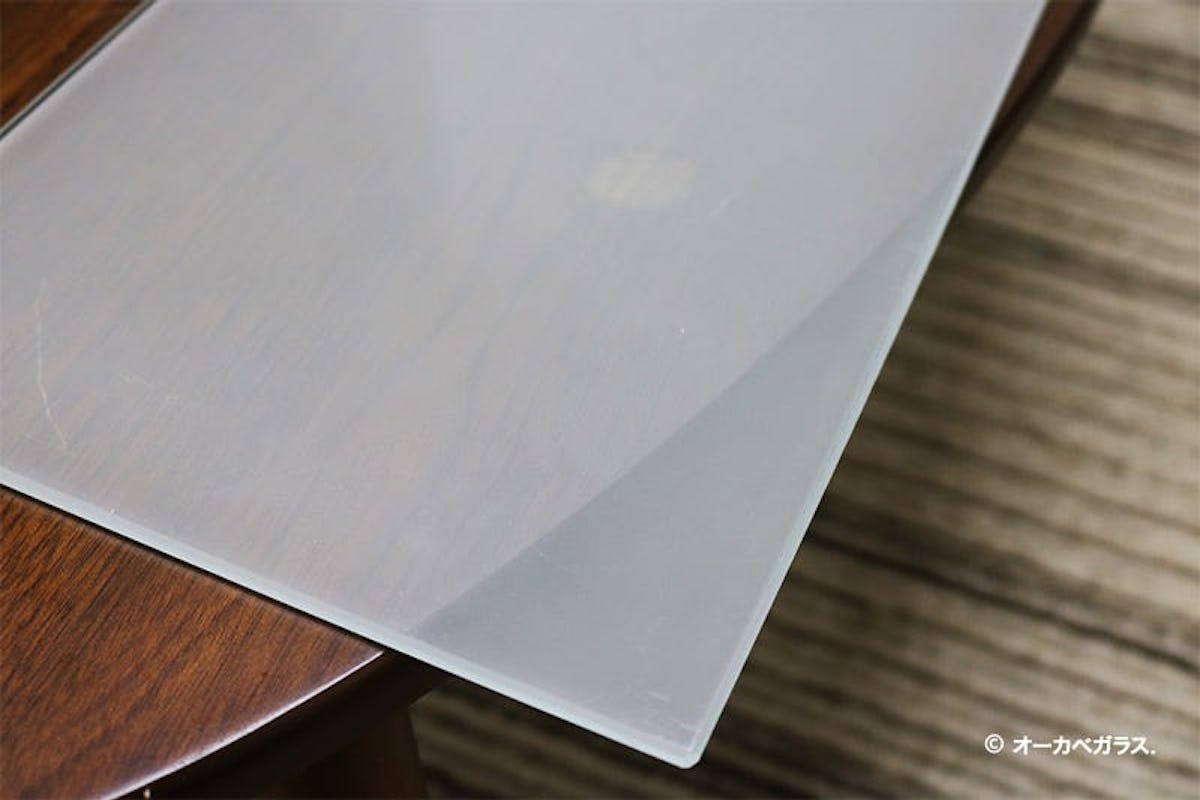 傷の付いたテーブルに「セラミックプリントガラス ミストホワイト(プレーン)」置いた様子